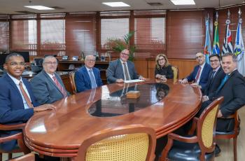 representantes da OAB de Bebedouro em mesa oval de madeira no gabinete da presidência, com a Dra. Ana Paula e Dr. Polastro