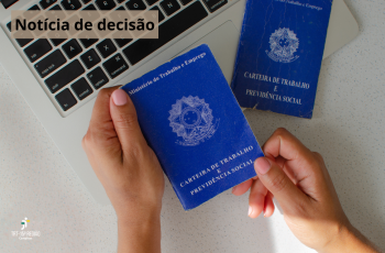 teclado de notebook com mãos femininas segurando uma carteira de trabalho com outra do lado.