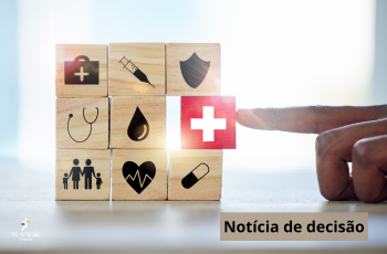 A imagem mostra blocos de madeira empilhados com ícones relacionados à saúde, como uma seringa, um escudo, um estetoscópio, uma gota de sangue, uma família, um coração com batimentos e um comprimido. Ao centro, destaca-se um bloco vermelho com uma cruz branca, símbolo universal da saúde, sendo empurrado por um dedo. No canto inferior esquerdo está o logotipo do TRT-15, e no canto inferior direito, a inscrição “Notícia de decisão”.