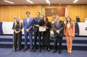 seis pessoas posam em pé para foto. Duas estão segurando um certificado.