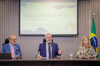 Dr. Edmundo, Dr. Lobo e Dra. Antônia estão sentados à mesa de trabalhos no auditório da Ejud-15