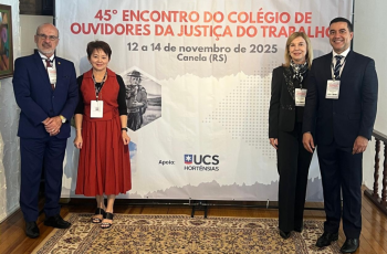 Comitiva do TRT-15 posa para foto em frente ao banner alusivo ao evento