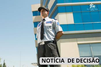 Um homem com uniforme de segurança em frente à uma universidade.
