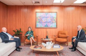 foto das três autoridades sentadas em sofás no gabinete da Presidência. Ao fundo, painel de madeira com um quadro. Na sala, uma mesa de centro.