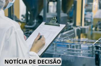 funcionário de jalego e itens de segurança escreve em papel na prancheta com maquinário de medicamentos ao fundo