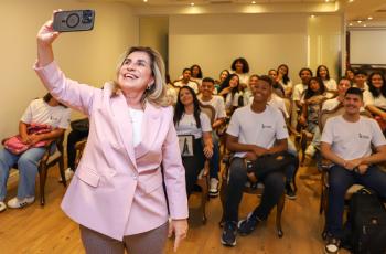 Dra. Ana Paula tira selfie com os aprendizes que estão sentados nas cadeiras do salão nobre