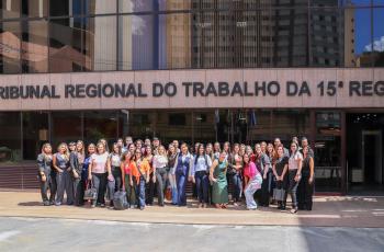 Estudantes e professores estão em pé em frente ao prédio do TRT-15