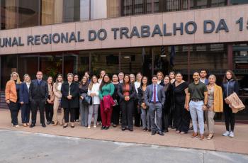 Grupo de pessoas posa para foto em frente ao prédio do TRT-15