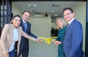 Quatro pessoas, dois homens e duas mulheres desfazem o laço inaugural na porta do novo prédio.