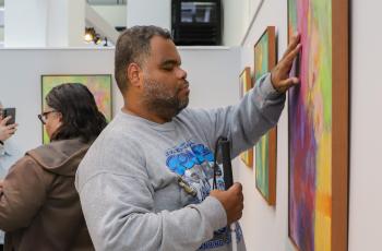 Um rapaz deficiente visual passa a mão em uma das obras da artista.