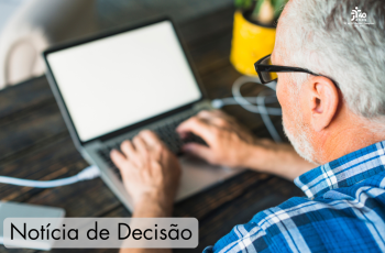 A foto mostra um trabalhador na faixa dos 65 anos de idade trabalhando num computador