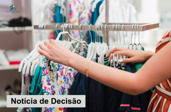 imagem mostra uma arara com roupas sendo organizada por uma mulher, que aparece parcialmente do lado direito.
