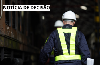 Banner retrata um empregado usando EPIs andando de costa entre duas locomotivas