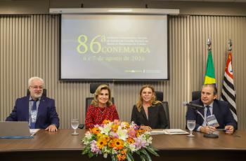 Quatro pessoas estão sentadas e posam para a foto, duas mulheres e dois homens.