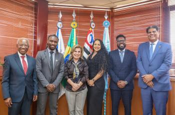 foto posada dos visitantes com a Dra. Ana Paula em frente as bandeiras em seu gabinete
