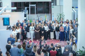Uma foto do alto com os servidores segurando suas respectivas medalhas. Todos em pé posam para a foto.