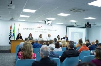 foto do auditório com mesa de trabalhos ao fundo e público sentado