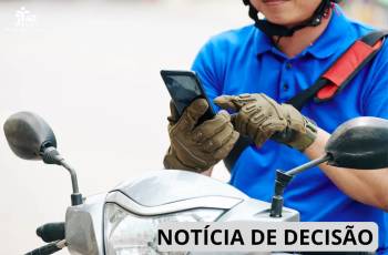 Um homem sentado na moto mexendo no celular.
