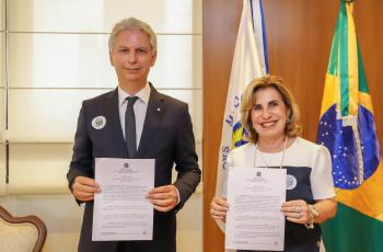 Ronaldo Lira e Ana Paula Lockmann posam para foto segurando o termo assinado