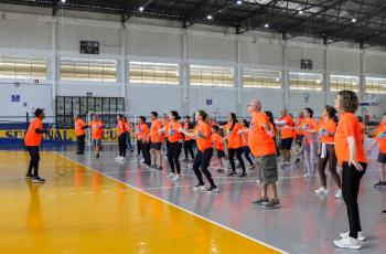 Servidores com camiseta laranja temática da semana fazem exercícios físicos em quadra poliesportiva